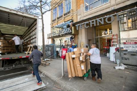 Men unload boxes from a moving truck outside of the Little Rock Technology Park building.